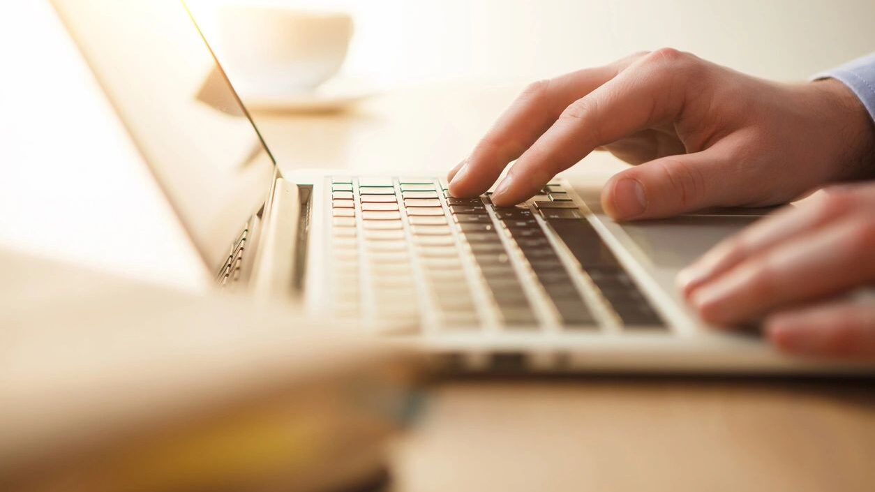 Photo of person typing keys on a computer. The image refers to how people process information quickly and how quality content that educates yields impact.